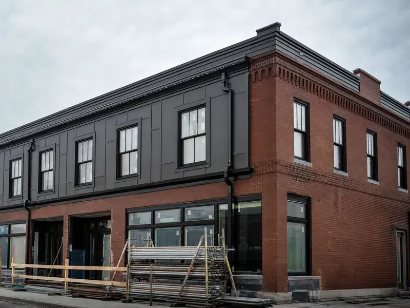 Brick commercial building receiving new cladding, windows, trim, and drainage details.